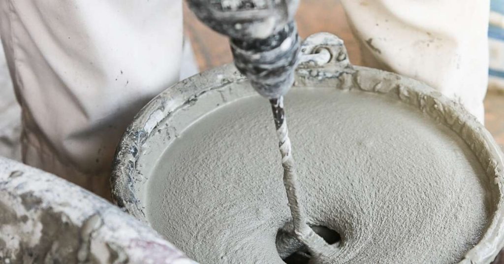 Electric mixer blending cement in a bucket