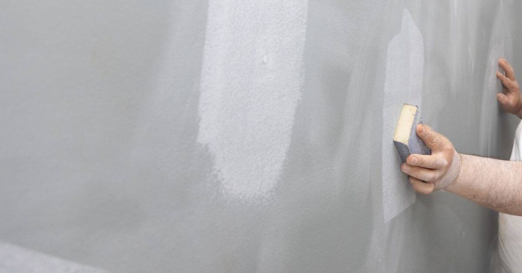 Hand applying sponge to textured plaster wall