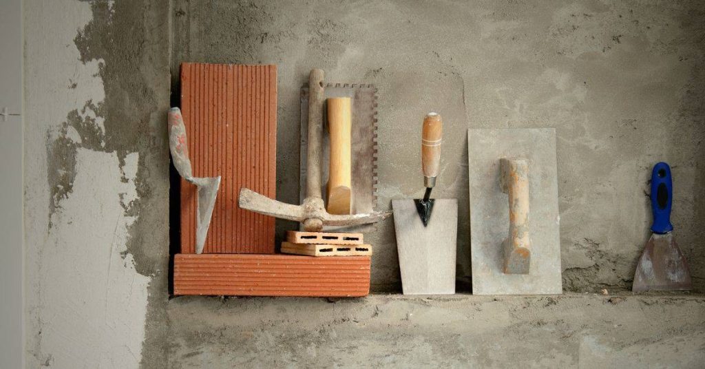 Masonry tools with bricks and cement on unfinished wall