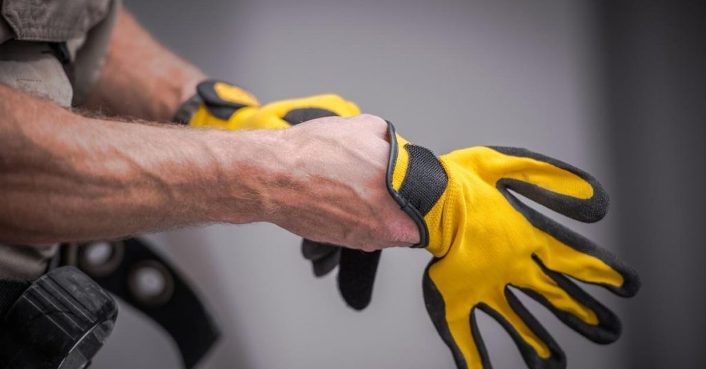 Person putting on yellow and black work gloves