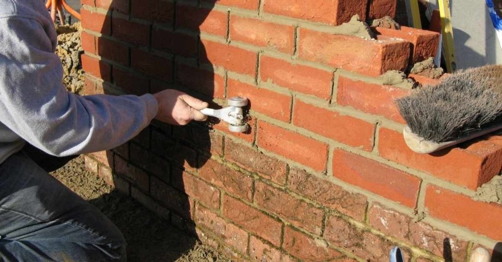 Person using roller tool on brick wall joints