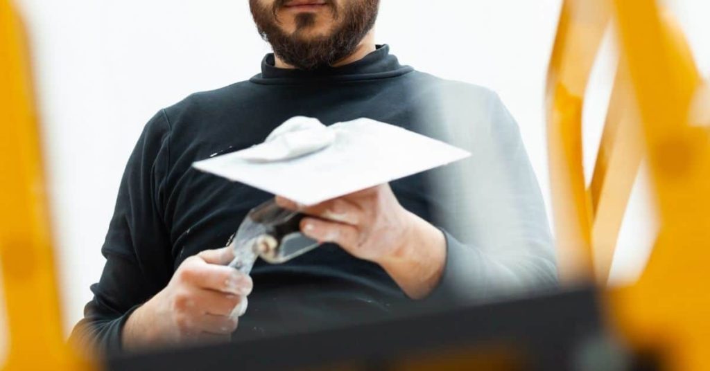 Plasterer holding trowel with plaster close up