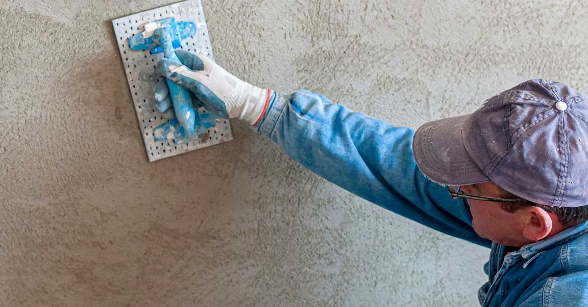 Person applying stucco texture to wall with a trowel