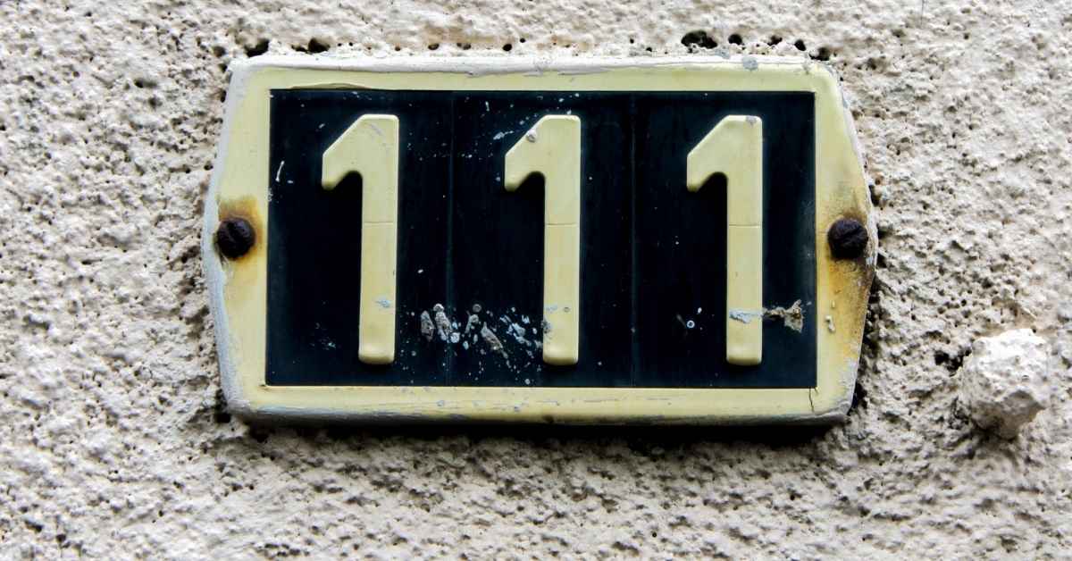 metal address plate with number 111 on stucco wall