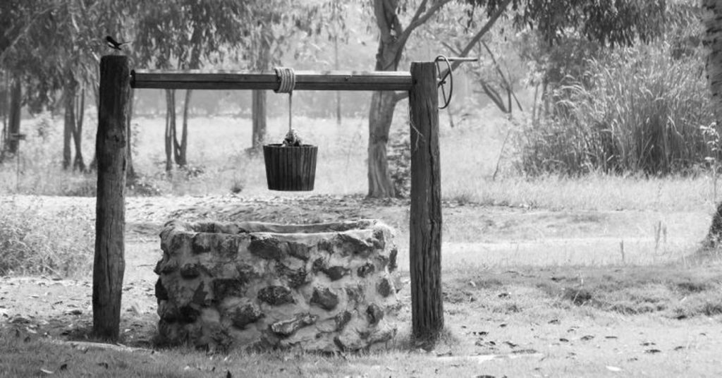 Stone water well with bucket hanging on pulley system