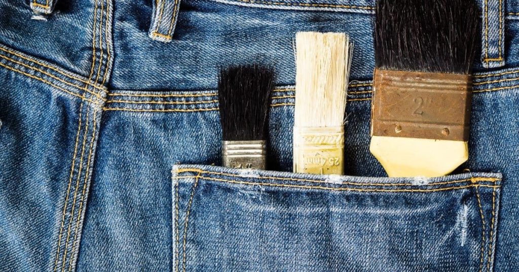 Three different paintbrushes in a blue denim pocket