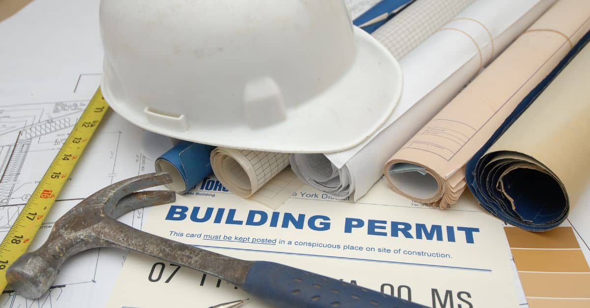 White construction helmet hammer measuring tape and rolled blueprints