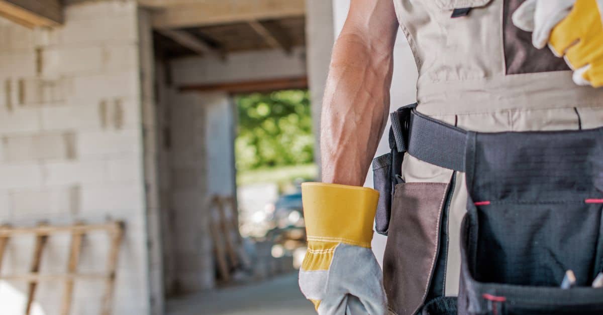 Construction worker wearing gloves and toolbelt at site