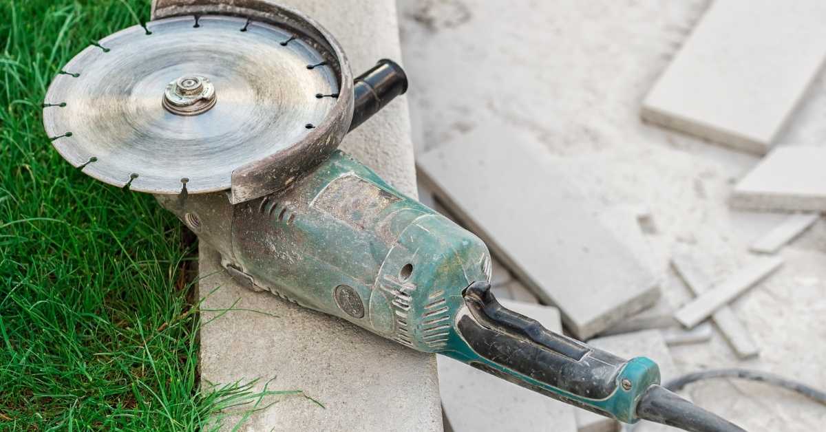 Angle grinder with diamond blade resting on concrete edge