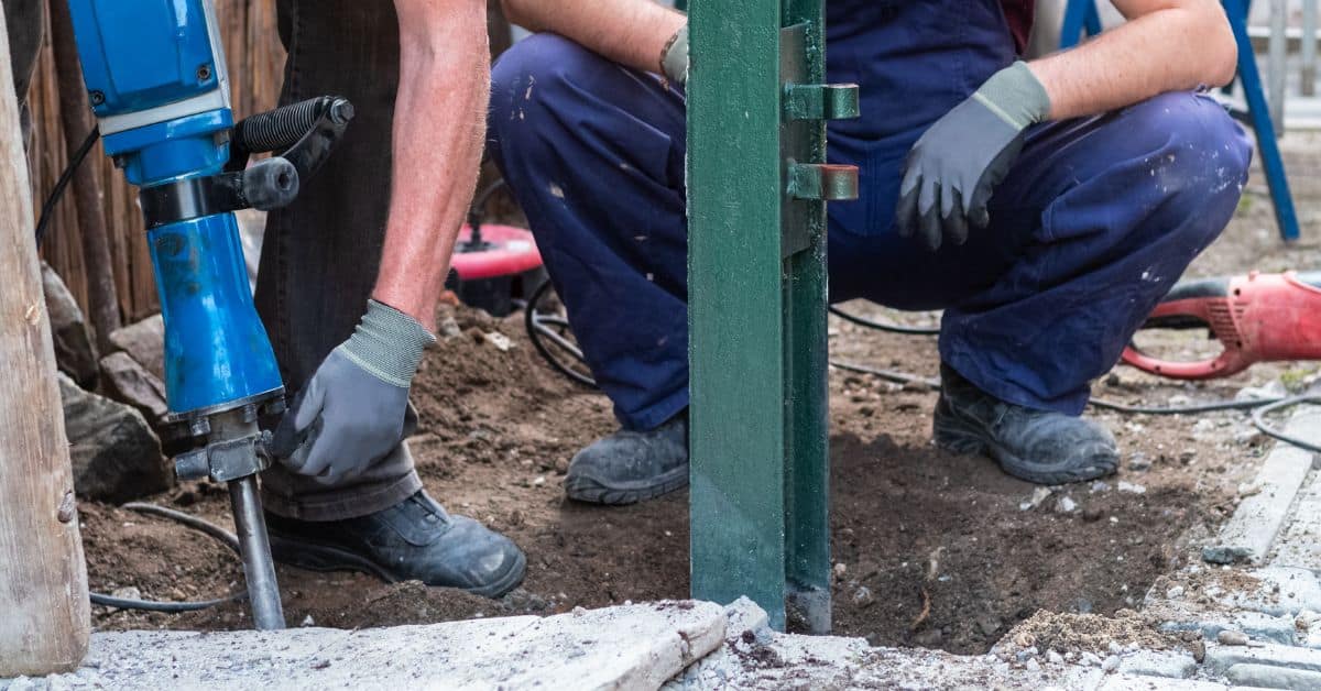 Person using electric jackhammer breaking concrete outdoors
