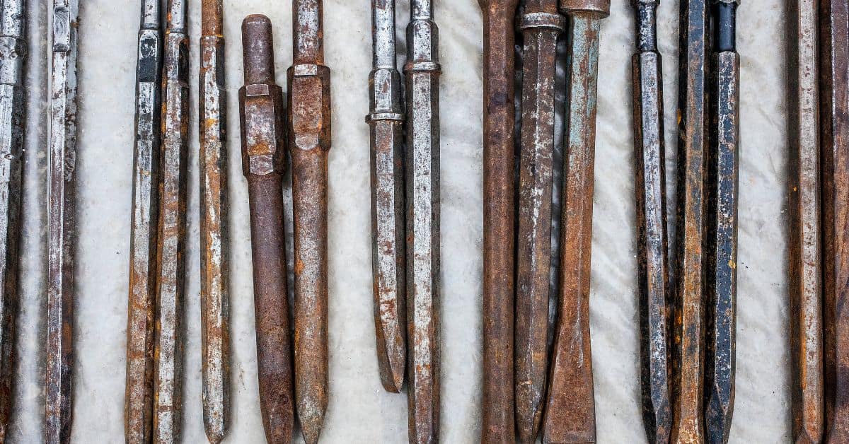 rusty concrete chisels and masonry tools laid out on surface