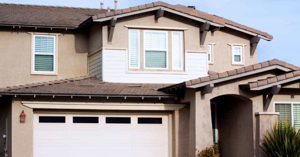 Two-story stucco house exterior with windows and garage door