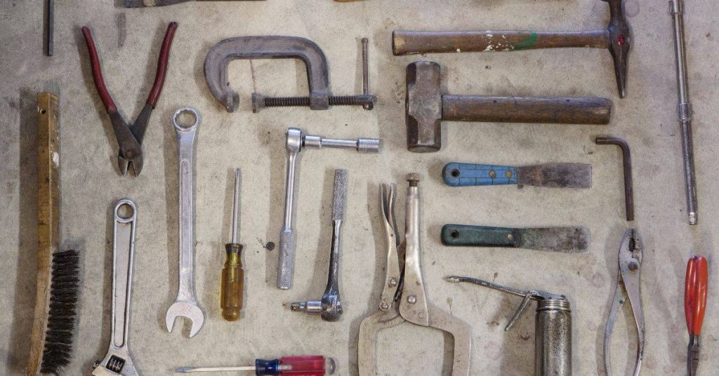 Various hand tools laid out on a concrete surface