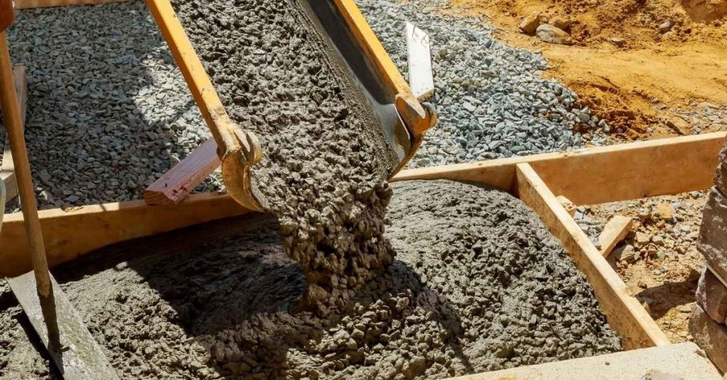 Wet concrete pouring into wooden forms outdoors