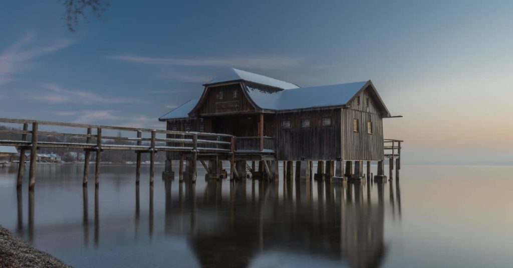 Wooden house on stilts over calm water at sunset