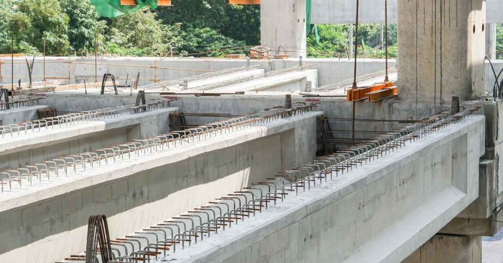 Reinforcing bars project from unfinished concrete beams and walls at a construction site.