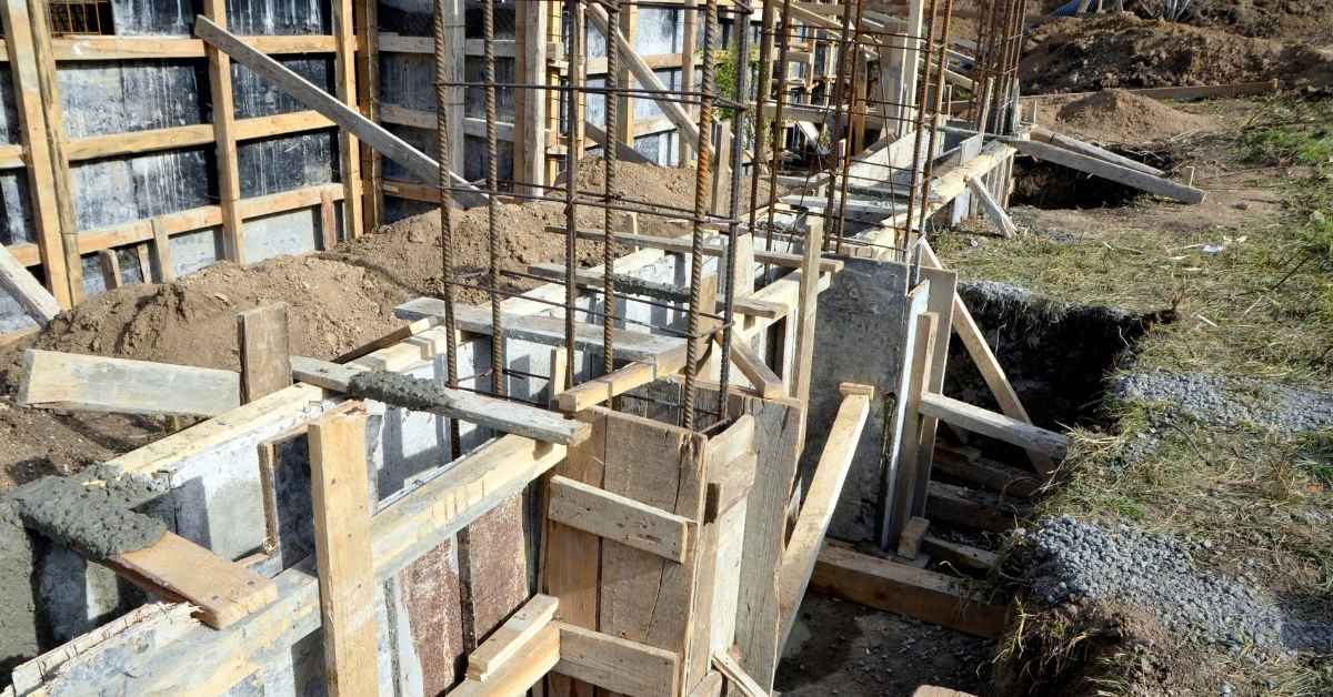 Vertical reinforcing bars assembled inside wooden concrete formwork at a foundation construction site