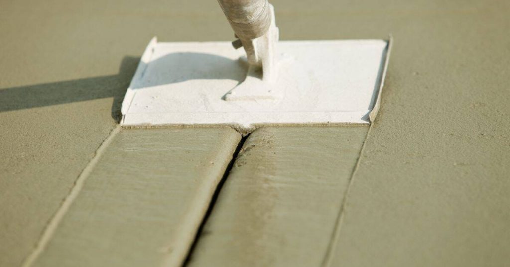 Hand float smoothing freshly placed concrete beside a straight line in the slab surface