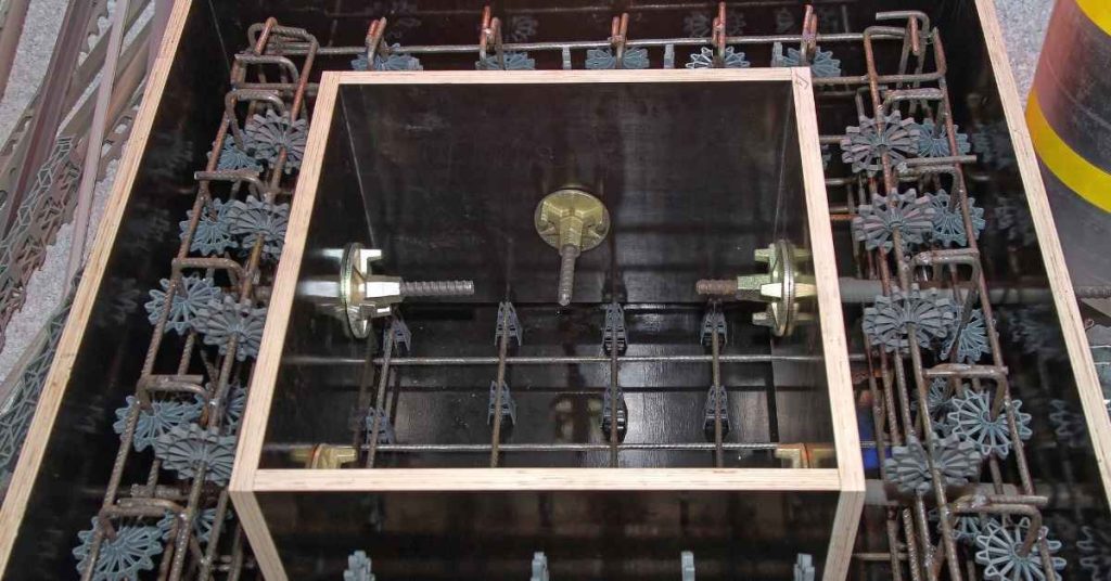 Open concrete form showing reinforcing steel, tie hardware, and plastic spacers before pouring.