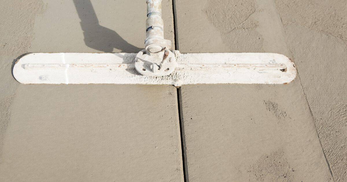 Concrete finishing tool smoothing a slab beside a straight joint