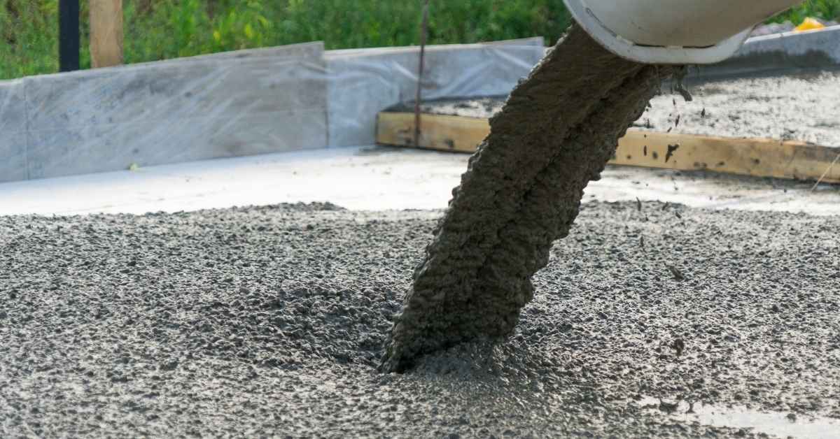 Fresh concrete being poured from a chute onto a slab within wooden formwork